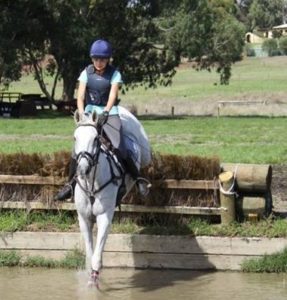 Laurie on her horse going over a water jump